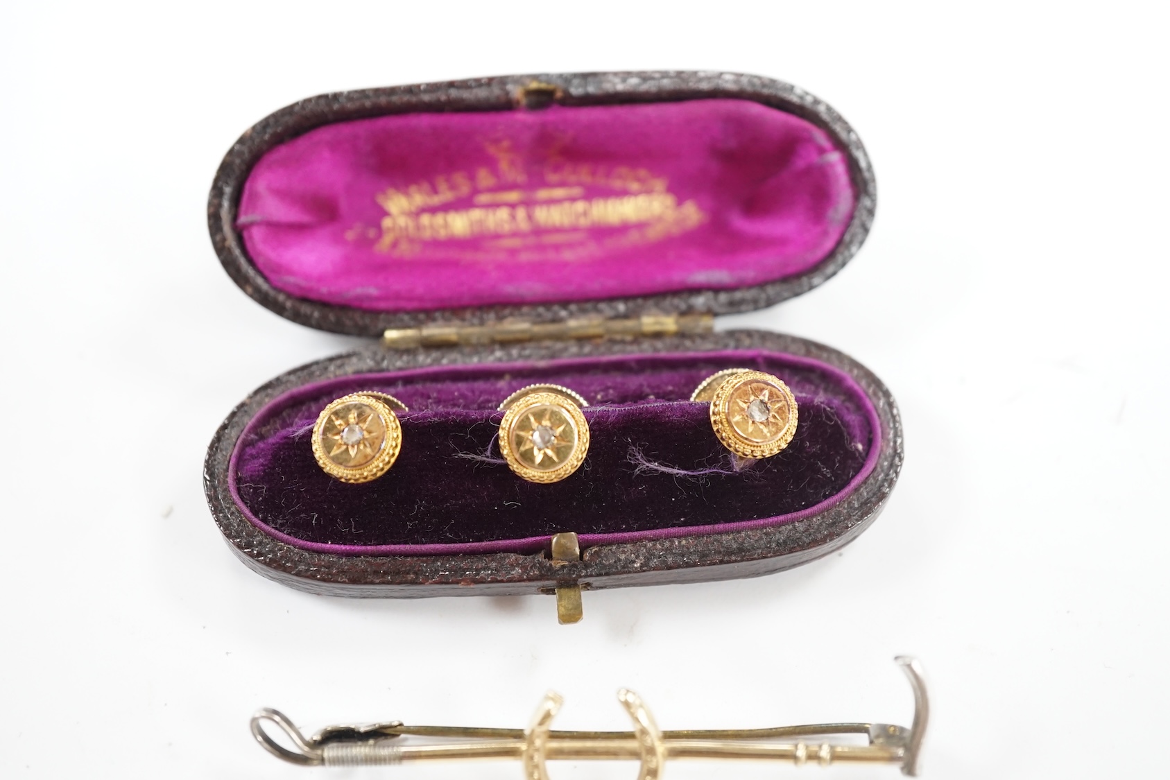 An Edwardian cased set of three 9ct and rose cut diamond set dress studs and a 9ct and silver riding crop and horseshoe bar brooch. Condition - fair